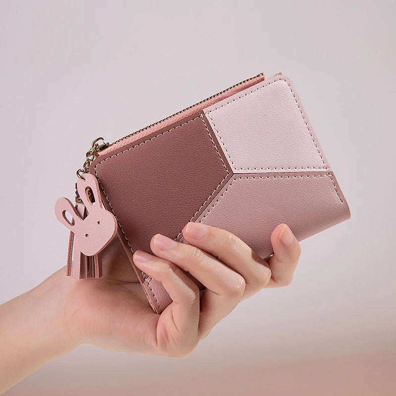 Hand holding a pink geometric wallet with a bunny charm on a light background