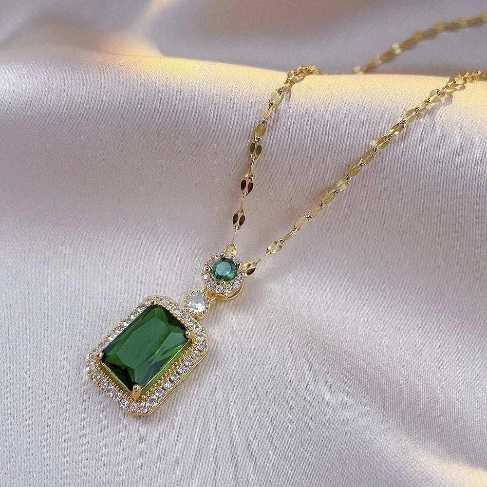 Gold necklace with a green gemstone pendant on a white background